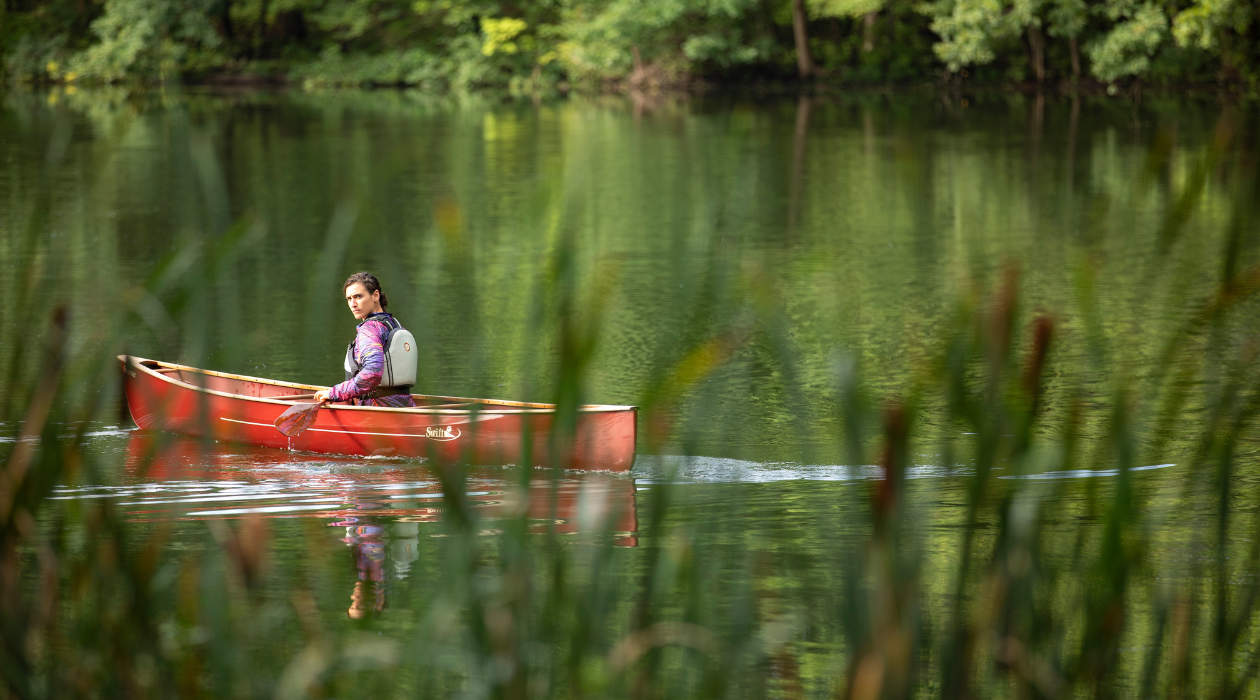 Person in red canoe paddles Ferncliff Pond